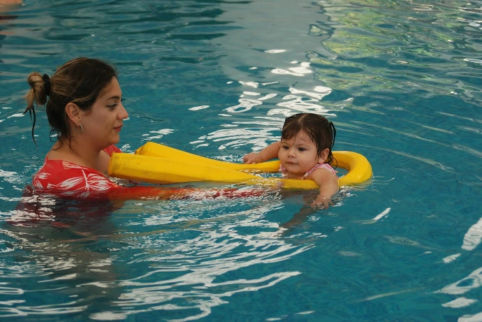 A woman holding a child in a swimming pool